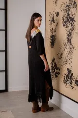 Vestido corto negro de tejido de punto con cuello en V, mangas 3/4, flecos en el ruedo y apliques de cuero en escote y hombros.