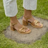 Sandalias de cuero color dorado, con plataforma y taco cuadrado. Presentan tiras cruzadas en el empeine y pulsera al tobillo con hebilla.
