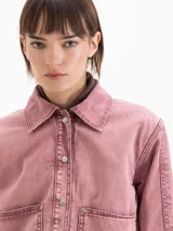 Chaqueta de gabardina color rosado con efecto desgastado, de calce relajado, cuello clásico marrón, bolsillos delanteros aplicados y cierre frontal con broches metálicos a presión.