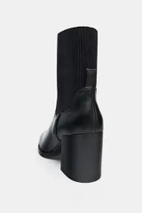 Botín de tacón alto en bloque con cuerpo de cuero sintético y caña de tejido elástico acanalado. Presenta punta redonda y diseño minimalista.