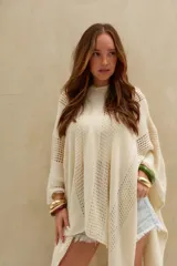 Poncho de tejido de punto color crudo, con capucha y diseño amplio.