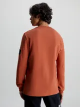 Remera de manga larga con cuello redondo y puños de canalé, confeccionada en punto gofrado de algodón. Presenta una insignia con el logo de Calvin Klein en la manga.