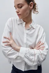 Camisa de viscosa color celeste, de calce amplio y caída fluida, con cuello clásico, cierre frontal de botones y detalles calados en mangas y delantero.