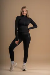 Conjunto deportivo negro compuesto por calza, musculosa y campera con cierre.