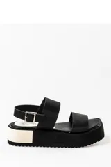 Sandalias negras de cuero con plataforma blanca y hebilla metálica.