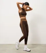Pantalón legging deportivo Get Over de tiro alto, confeccionado en microfibra seamless de color marrón con detalles laterales en tono tostado y cintura ancha acanalada.