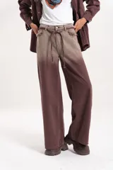 Jean wide leg de tiro medio con efecto desteñido en tono marrón y detalles desflecados en los bolsillos delanteros. Incluye un lazo de tela ajustable en la cintura.