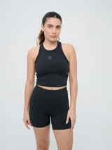 Top deportivo Umbro modelo Kia color negro, sin mangas, con cuello redondo y diseño crop top. Cuenta con el logo de la marca estampado en el centro del pecho.