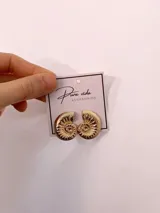 Aros dorados con diseño en relieve de caracol o amonite, de acabado brillante.