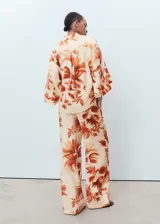 Pantalón tiro medio de tejido fluido con diseño recto y largo, con estampado de palmeras, bolsillos laterales y forro interior.