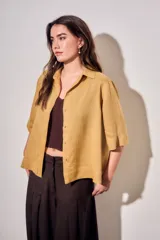 Camisa de lyocell color mostaza, de corte holgado, mangas cortas y cierre frontal con botones.