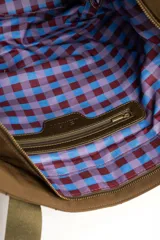 Bolso tipo tote bag color marrón con diseño capitonado de ondas, asas largas y placa metálica con el logo de la marca.