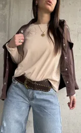 Remera manga larga de color beige, con cuello redondo y diseño bordado de flores en el hombro y lateral.