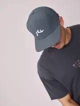 Gorra de visera curva color gris oscuro, confeccionada en tejido ripstop con detalle de logo bordado en blanco en el frente.