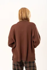 Buzo de punto color chocolate con diseño de flor grande en el frente en tonos rojos y centro texturizado en color crema. Presenta cuello redondo, mangas largas y puños y ruedo acanalados.