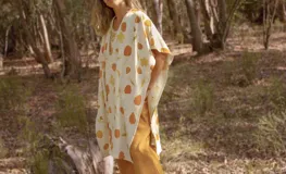 Ruana abierta color crema con estampado de hojas color naranja.