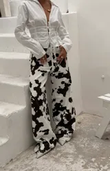 Pantalón de jean blanco con estampado de manchas de vaca en negro, de corte recto y tiro alto.