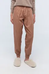 Pantalón estilo babucha color marrón, con pinzas en la cintura y puños elásticos en los tobillos.