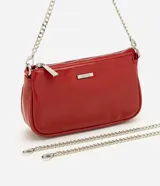 Cartera tipo baguette pequeña Satinato, confeccionada en PU color marfil, de formato alargado y estructura maleable. Cuenta con cierre superior de cremallera, placa frontal aplicada con el logo de la marca y asa de cadena doble metálica en tono plateado que permite llevarla al hombro o cruzada.