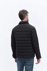 Campera puffer negra de líneas horizontales, con cuello camisero y cierre frontal oculto. Presenta un diseño minimalista con bolsillos laterales funcionales.