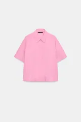 Camisa azul de manga corta y cuello solapa con costura horizontal en el pecho y cierre frontal oculto con botones.