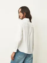 Camisa de manga larga con cuello clásico y cierre frontal de botones, confeccionada en tela con acabado satinado.