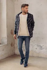 Sobrecamisa de corte holgado con diseño a cuadros en tonos azul marino y marrón, confeccionada con forro interior de corderito sintético, cuello clásico, cierre frontal de botones y bolsillos en el pecho.