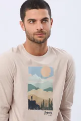 Remera de manga larga en color azul oscuro, con cuello redondo y estampado frontal de paisaje montañoso. Presenta un pequeño parche decorativo en la manga.