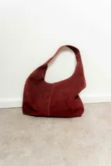 Bolso tote de gamuza color bordó con asa de hombro.