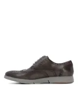Zapato tipo Oxford con diseño brogue, confeccionado en cuero color marrón oscuro. Presenta cordones al tono y una suela de goma gris con diseño deportivo.