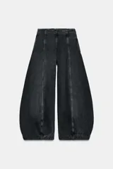 Jeans de tiro alto con diseño de pierna tipo balloon, confeccionados en denim de color gris oscuro con efecto lavado. Presentan costuras verticales marcadas a contraste, bolsillos laterales ocultos y cierre lateral con cremallera.