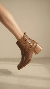 Bota tipo chelsea de cuero negro con paneles elásticos laterales y taco cuadrado de madera de 6 cm.