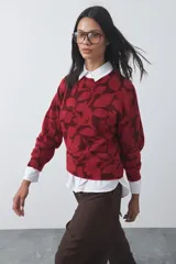Sweater de punto con diseño estampado floral en tonos rojos y bordó, de cuello redondo y mangas largas con puños acanalados.