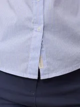 Camisa celeste a rayas verticales blancas, de manga 3/4 con puños arremangados y cuello clásico.