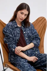 Campera de denim azul con estampado estilo paisley, cierre frontal con botones metálicos y cuello camisero.