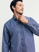 Camisa celeste con microestampado blanco, de corte clásico, manga larga y cuello abotonado. Tiene un bolsillo en el pecho.
