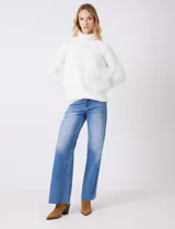 Polera de punto grueso color blanco, con cuello alto, mangas largas de corte ranglan y diseño de texturas combinadas.