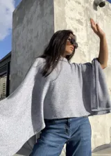 Poncho de hilo liviano en color gris claro, con cuello alto y diseño de caída fluida y holgada. Es una prenda versátil ideal para media estación.