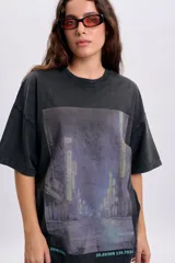 Remera oversize gris oscuro con estampa frontal de paisaje urbano nocturno y las inscripciones "SHINJUKU" y "35.6938N 139.7034" en la parte inferior.