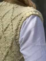 Chaleco tejido en lana merino con diseño de rombos en relieve, cierre frontal con botones de guampa y detalles en cuero.