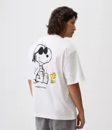 Remera boxy de algodón color blanco, con cuello redondo, manga corta y estampa en la espalda de Snoopy con anteojos de sol y Woodstock, junto a la inscripción "Takin' It Easy".