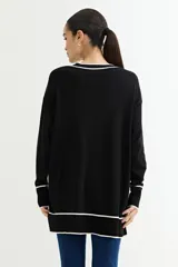 Sweater negro de tejido de punto con escote en V y ribetes blancos en cuello, puños y ruedo.