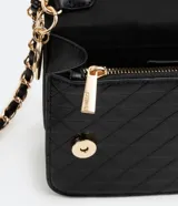 Bolso pequeño estructurado color negro, con textura capitoneada, asa de cadena y solapa frontal con botón a presión. Incluye divisor interno con cremallera.