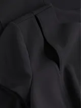 Vestido negro de corte ajustado, con largo a la rodilla, mangas cortas y cuello redondo. Presenta un cierre de cremallera en la parte posterior y recortes en los hombros.