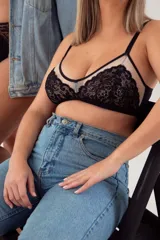 Bralette negro de encaje con copas triangulares de tul y espalda de lycra. Breteles elásticos regulables y ganchos regulables en la espalda.
