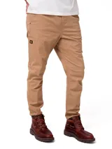 Pantalon de gabardina color beige, de corte ajustado y estilo utilitario. Cuenta con cintura elástica con cordón de ajuste, bolsillos laterales, un bolsillo utilitario en la pierna derecha con etiqueta de la marca Caterpillar y remaches metálicos.