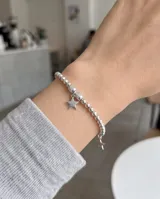 Pulsera de plata elaborada con cuentas esféricas texturizadas y dos dijes colgantes en forma de estrella.