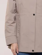 Campera impermeable Gallery de color beige, con capucha plegable, cierre frontal oculto con botones a presión, bolsillos delanteros y cordón de ajuste en la cintura.