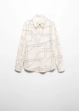 Camisa de corte recto y tejido fluido, con cuello camisero, cierre frontal de botones y mangas largas con puños abotonados. Presenta un estampado geométrico lineal sobre fondo color crema.