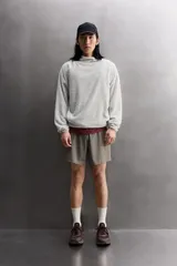 Sudadera regular fit de tejido polar con textura efecto pelo, color gris claro. Cuenta con cuello subido, capucha ajustada, manga larga ranglán, bolsillos laterales en la cadera y bajo asimétrico más largo en la espalda. Los acabados son con cinta elástica.